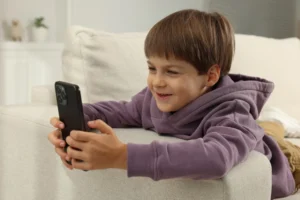 Un niño pequeño sonriente utilizando un smartphone, ilustrando el uso temprano de teléfonos inteligentes en la infancia